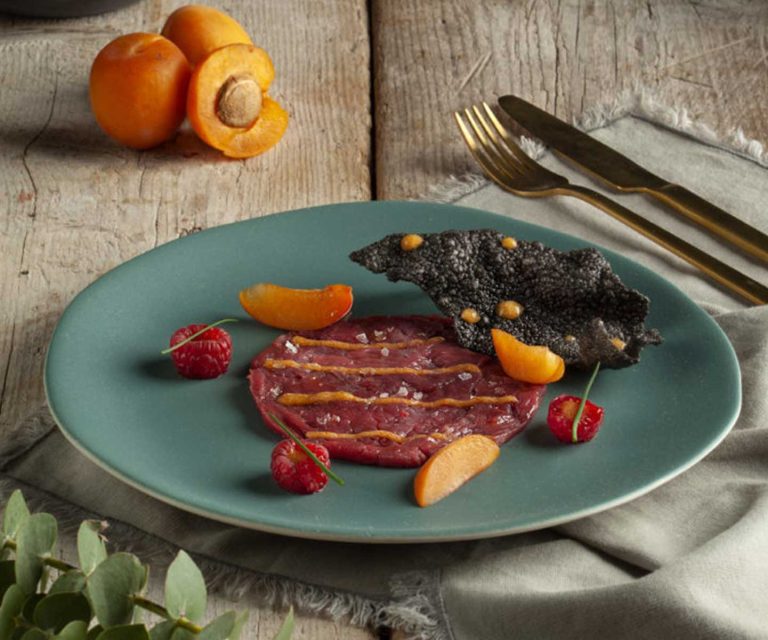 Carpaccio di noce di manzo, cialda di riso nero, gel di albicocca e lamponi
